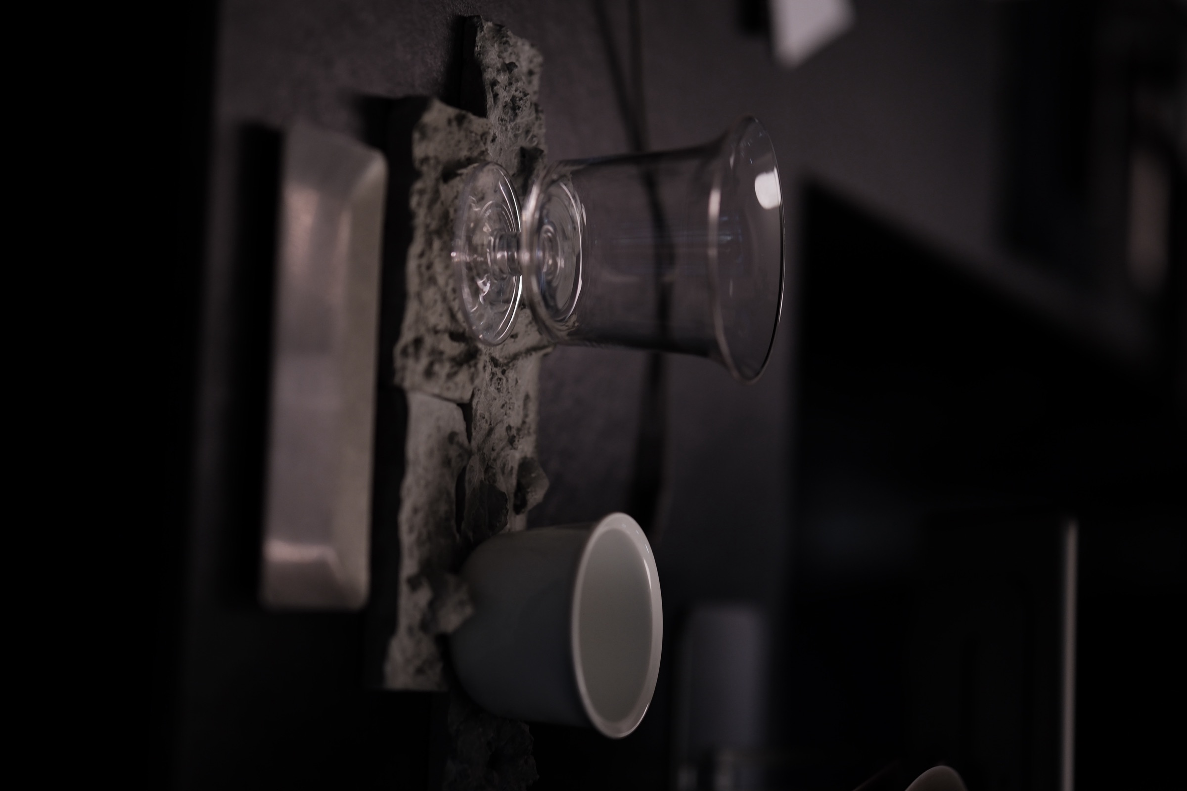 A glass and a white teacup on a dark tabletop