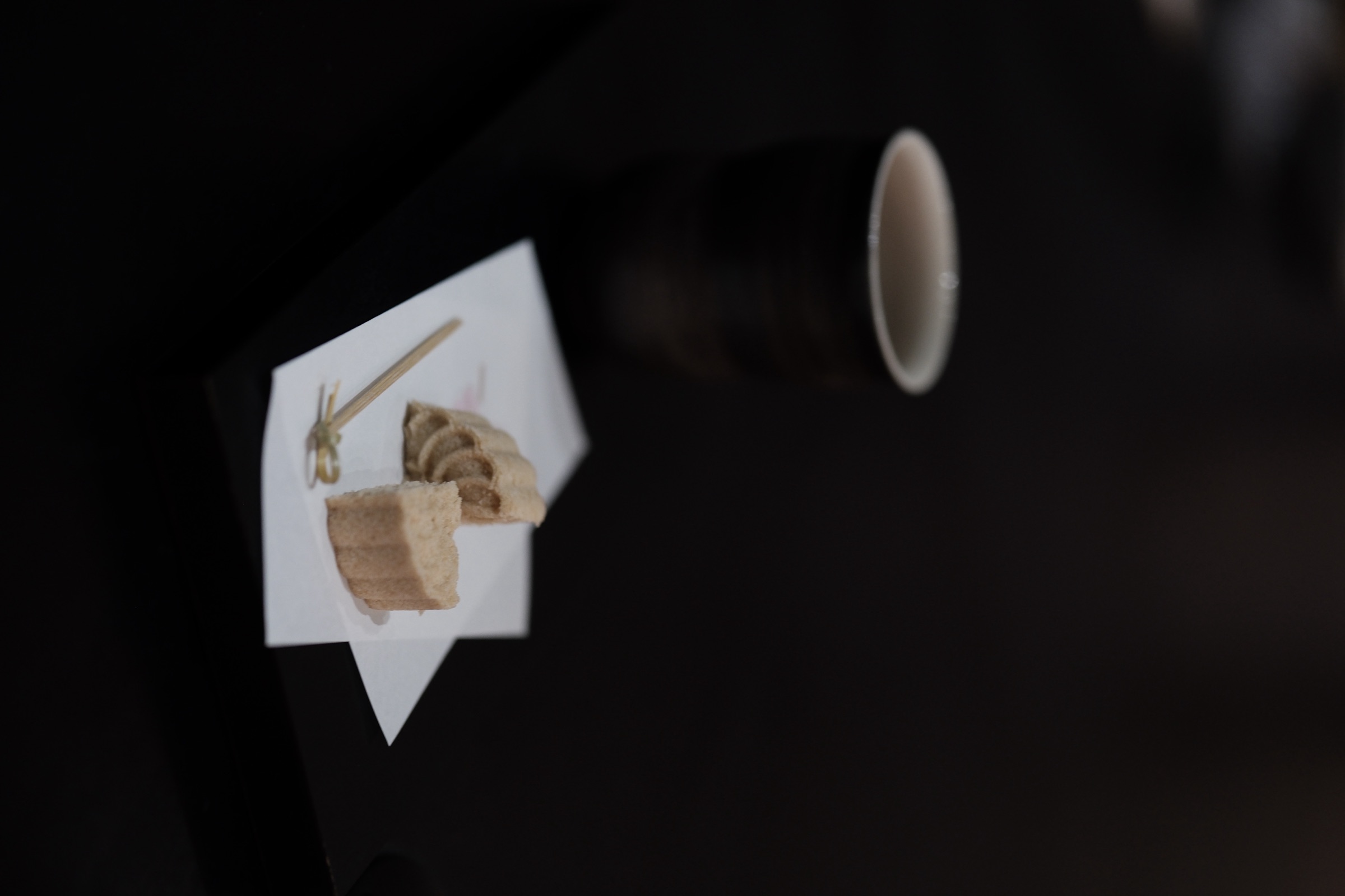 A sweet and a teacup on a dark tabletop