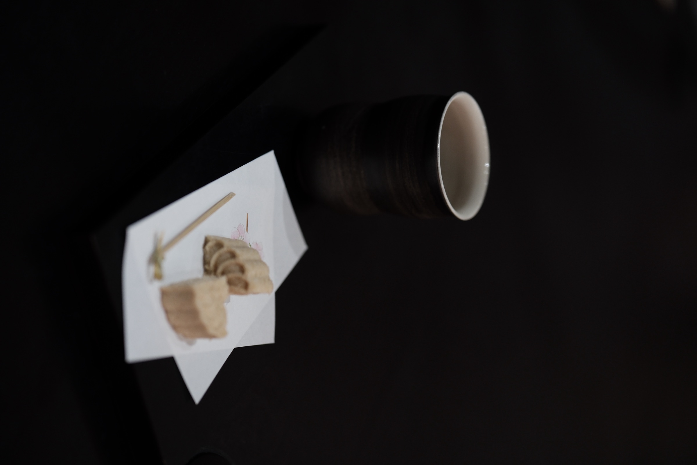 A teacup and a sweet on a dark tabletop